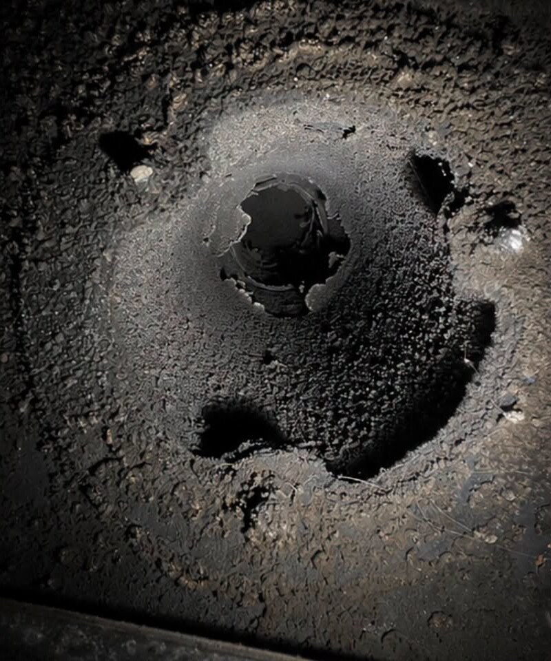 A flue collar caked in soot, the opening almost completely blocked