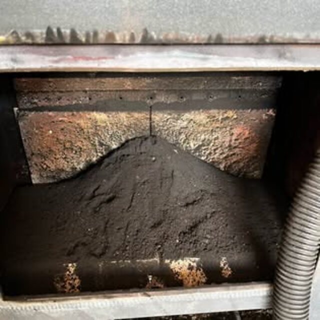 A stove firebox packed with soot before cleaning